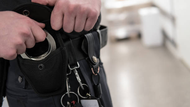 Police offiser or security staff takes up handcuffs for arrest of criminal. stock photo