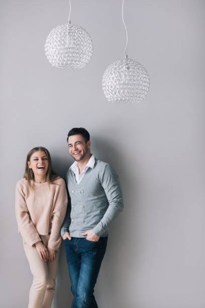 istock Young Laughing Couple at home standing on gray. 955808334