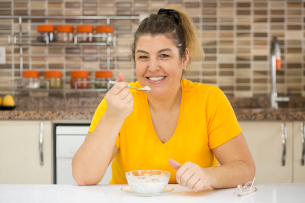 istock Happy fat woman eating healthy breakfast 955812114