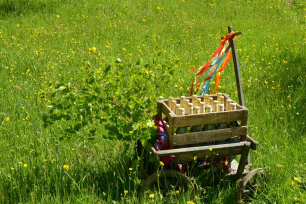 A handcart with a blanket, a beer box, colorful ribbons on a wonderful spring meadow for fathers day