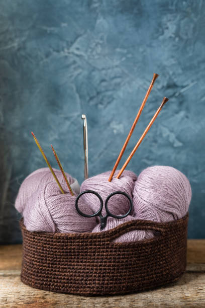 istock Knitting accessories needles scissors hook with pink wool yarn in the crocheted basket 955833602
