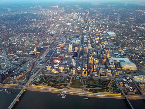 An aerial view of St. Louis at sunrise across the Mississippi River with the Gateway Arch in the foreground.