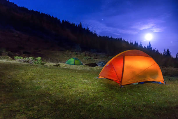 istock Two Illuminated orange and green camping tents 955834054