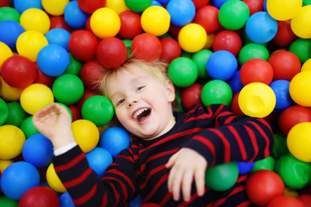 istock Happy little boy having fun in ball pit with colorful balls 955840804