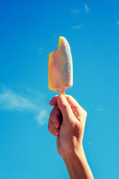 istock Ice cream in hand hold up.  on daytime and bright sky. 955843032