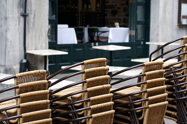 Folded wooden chairs and tables leaning against the wall of a house. Restaurant closed due to Corona pandemic.
