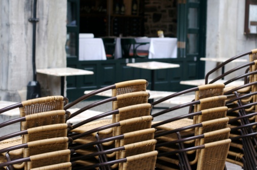 Elegant wooden table and empty chairs near the cafe against the background of the window and the wall of the old city.