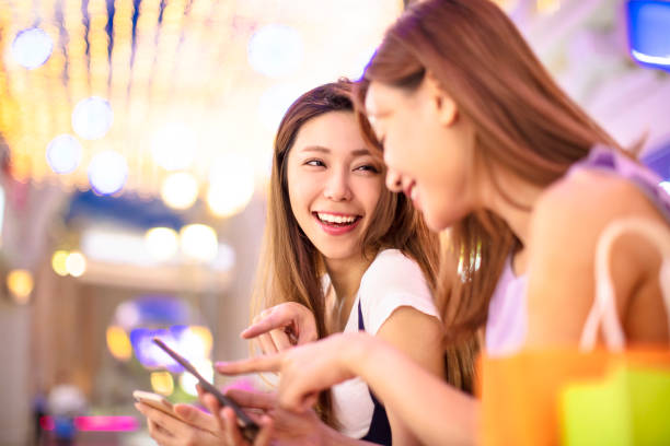 happy girls watching phone in the shopping mall happy girls watching phone in the shopping mall shopping asia stock pictures, royalty-free photos & images