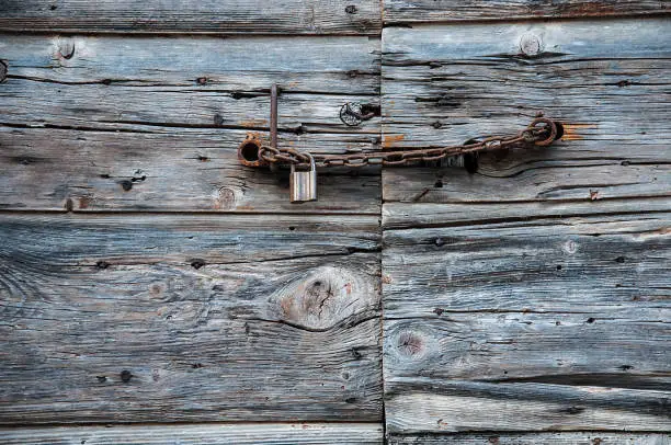 Detail of rusty chain and a padlock on the old wooden door with peeled blue paint, on the island of Vis in Dalmatia, Croatia