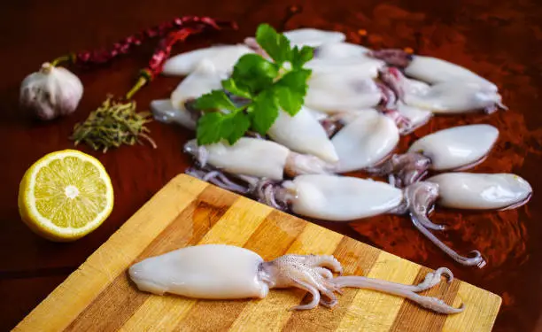 Photo of Fresh calamari. Squid. Seafood, lemon, garlic, pepper, parsley.