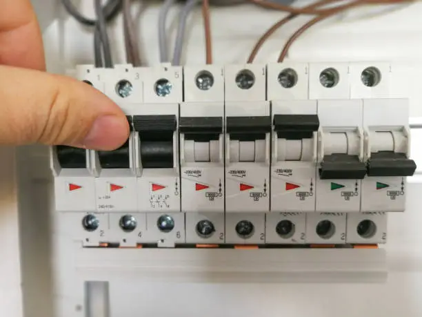 Photo of Electric engineer analyzes AC installation inside switch board cabinet