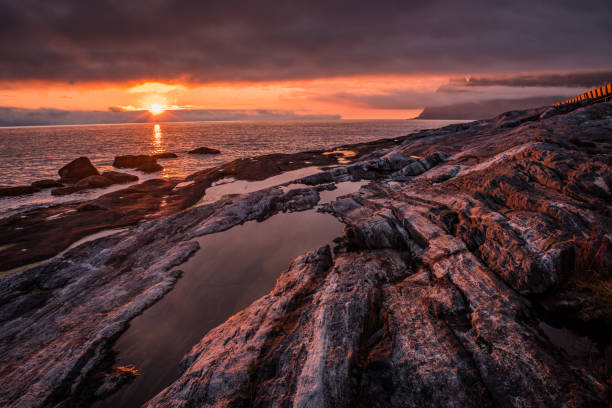 istock Dramatic, fiery sunset over the rocky shore with water puddles 955851382