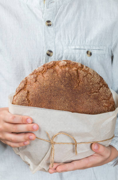 istock loaf of fresh rye bread in children's hands. Selective focus 955863880