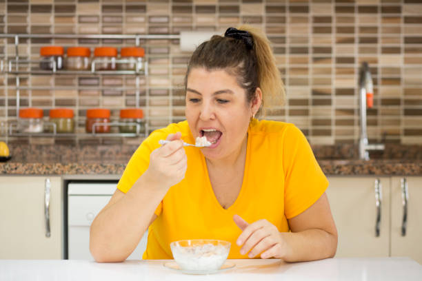 istock Happy fat woman eating healthy breakfast 955864416