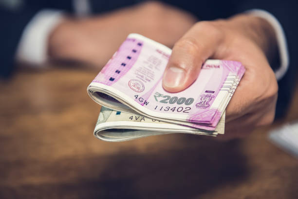 hombre de negocios dando dinero en forma de rupias indias por los servicios prestados - money roll fotos fotografías e imágenes de stock