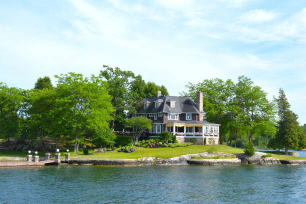 Island with house, cottage or villa in Thousand Islands Region in sunny summer day in Kingston, Ontario, Canada. 1000 Islands ON. Famous Canadian tourist vacation routs. St Lawrence River's Thousand Islands, Ontario Canada- June 19, 2016: Island with house, cottage or villa in Thousand Islands Region in sunny summer day in Kingston, Ontario, Canada. 1000 Islands near Gananoque, ON. Famous Canadian tourist vacation routs. kingston harbour stock pictures, royalty-free photos & images