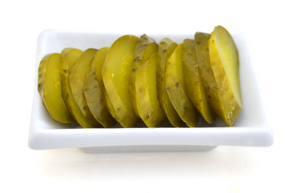 istock Fresh sliced green pickles in white plate over white 955889550