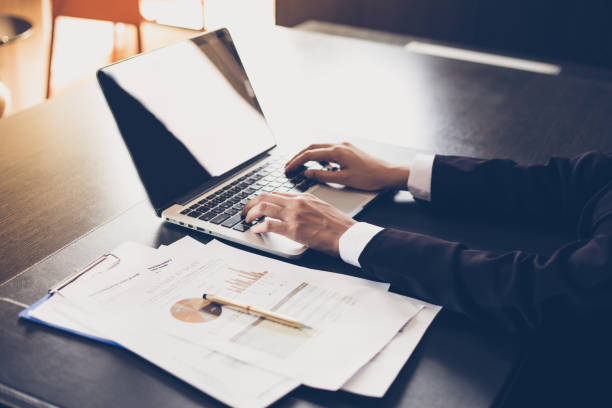 istock Asian businesswomen holding a pen and analysis documents on office table with laptop computer and graph financial diagram working in the background 955894856