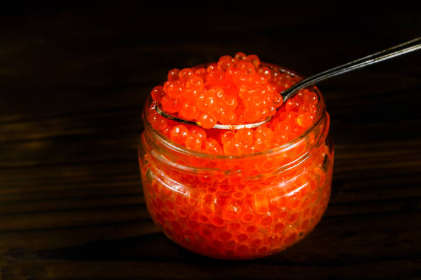 istock Red caviar in a spoon above the glass jar 955899772