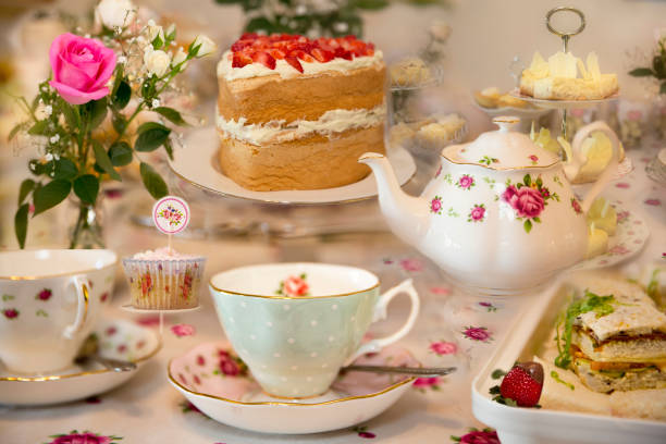 Set Up For High Tea A ladies morning, afternoon or high tea.  Also for an elegant party or celebration.  Teapot, cups and saucers, sponge cake and sandwiches. afternoon tea stock pictures, royalty-free photos & images