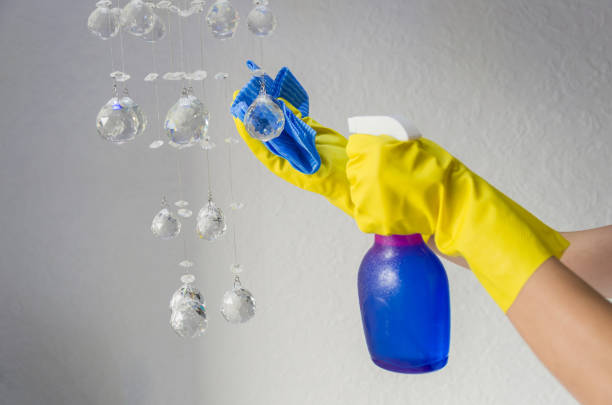 istock Great home cleaning concept, gloved hand wiping lighting chandelier crystals. 955902880