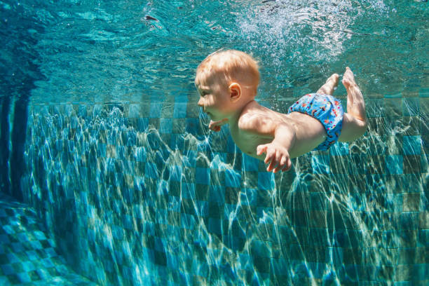 niño saltar bajo el agua en piscina - bebe bañandose fotografías e imágenes de stock
