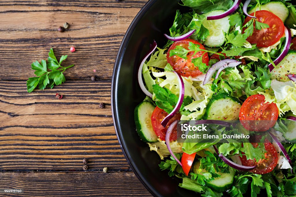 Salad from tomatoes, cucumber, red onions and lettuce leaves. Healthy summer vitamin menu. Vegan vegetable food. Vegetarian dinner table. Top view. Flat lay Salad Stock Photo