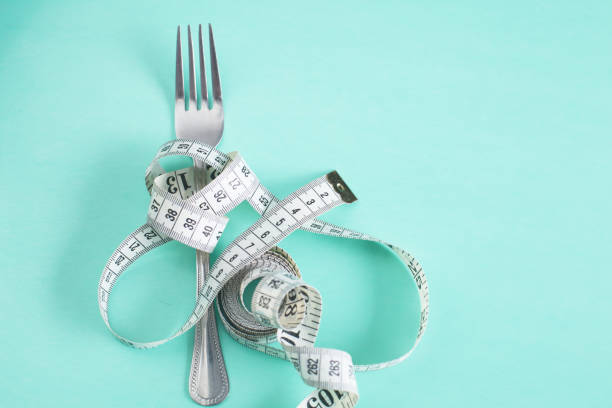 istock The fork is wrapped with a measuring tape on the table. Diet 955920502