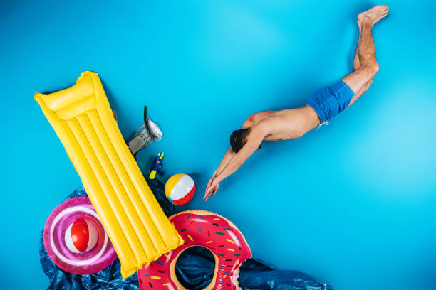 istock young man in shorts diving to various beach objects on blue, summer vacation concept 955933134