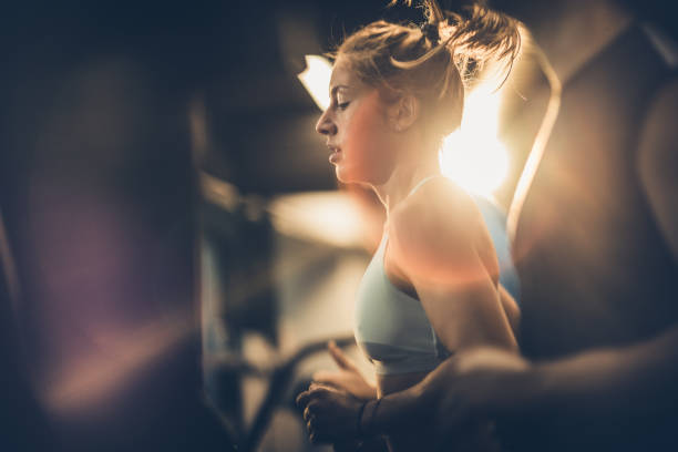 profile view of sweaty sportswoman warming up in a gym. - running women jogging profile imagens e fotografias de stock