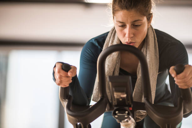 istock Athletic woman making an effort while cycling on exercise bike in a gym. 955937954
