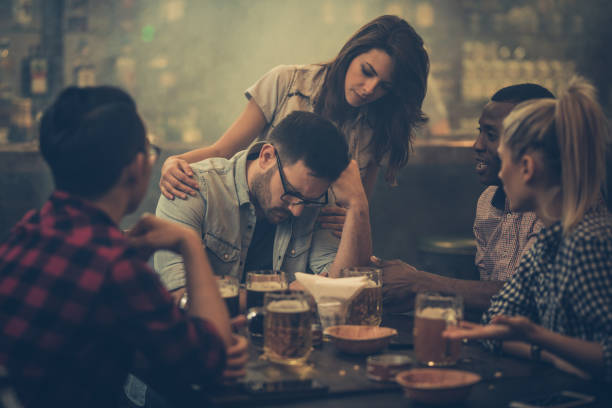 Don't be sad, everything will be ok! Group of friends consoling their friend who is sitting displeased in a bar. woman comforting depressed friend stock pictures, royalty-free photos & images