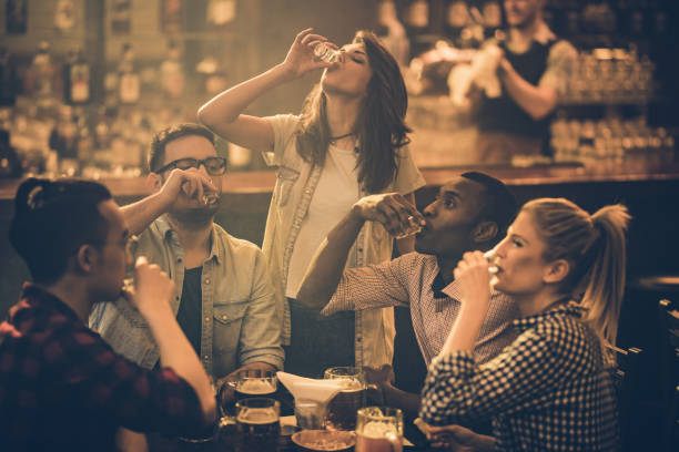 Group of young friends drinking tequila shots in a bar.