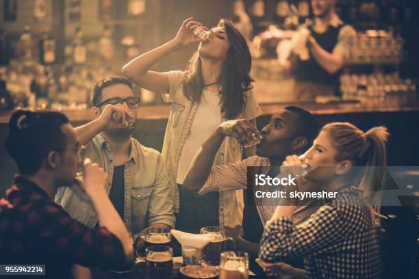 Group Of Young Friends Drinking Tequila Shots In A Bar Stock Photo - Download Image Now