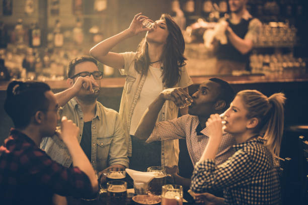 group of young friends drinking tequila shots in a bar. - tequila shot imagens e fotografias de stock