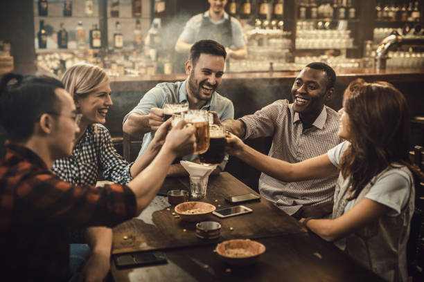 istock Young happy friends having fun while toasting with beer in a pub. 955942772