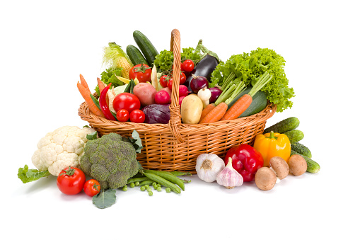 Wicker basket full with various fresh vegetables on white