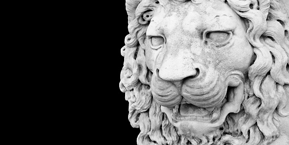 Sculpture of a medieval lion head of stone (Italy) - Image with copy space isolated on black background for easy selection