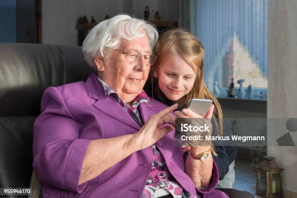 Nenek Menunjukkan Cucunya Sesuatu Yang Lucu Di Smartphonenya Foto Stok - Unduh Gambar Sekarang