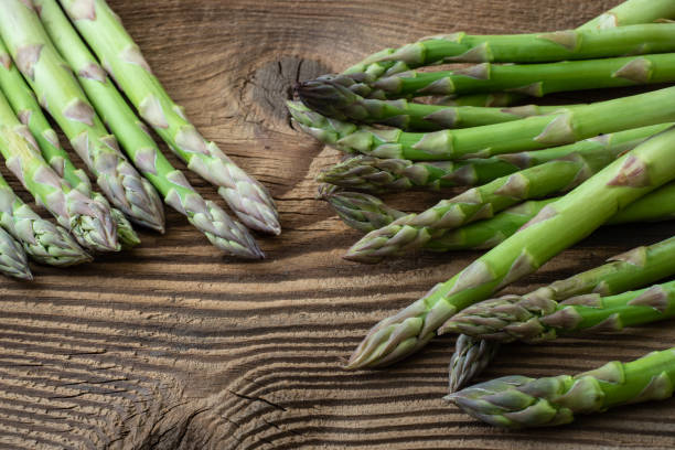 istock Raw garden asparagus stems. Fresh green spring vegetables on wooden background. (Asparagus officinalis). 955950996