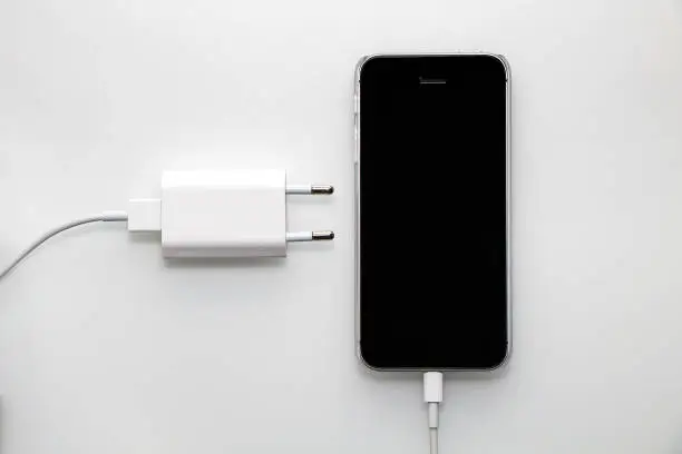 Photo of Black smartphone, adapter and cable on a white background