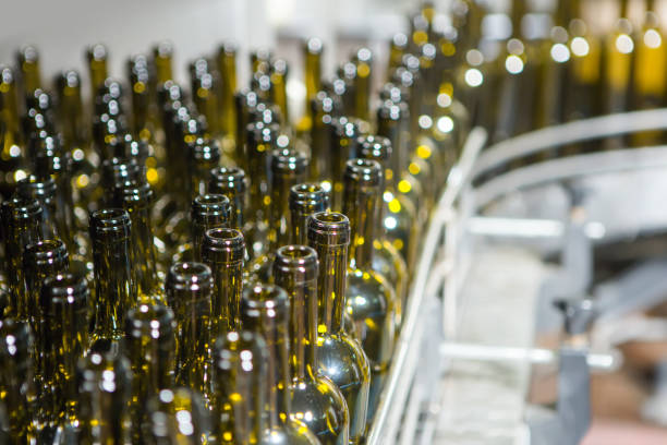 istock Unlabeled glass bottles in bottling machine at modern winery 955957644