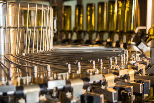 istock Unlabeled glass bottles in bottling machine at modern winery 955957828