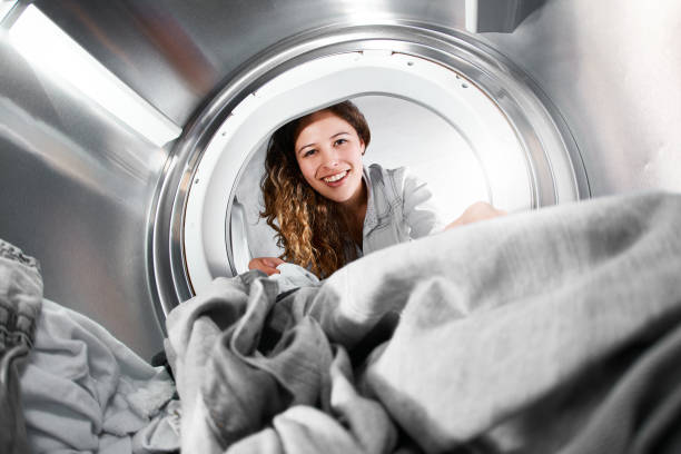 istock Seen from inside drum, woman loads tumble dryer 955959300
