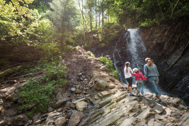 Сute family at fresh waterfall in green Carpathian Mountains
