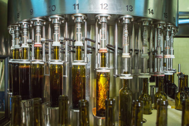 istock Unlabeled glass bottles in bottling machine at modern winery 955977512