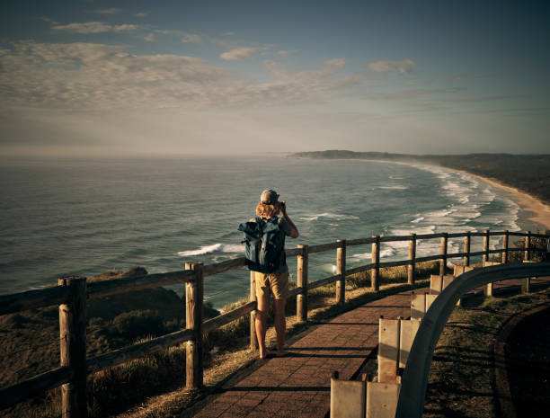Shot of a young man taking photos of the scenic landscape along the coast