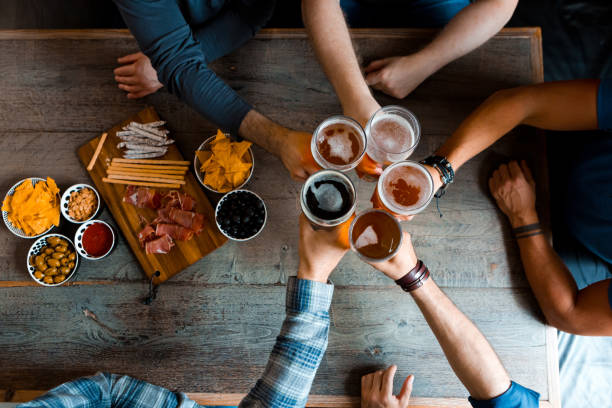 top view of friends toasting with beer above the table in pub - rustic beer brewery indoors imagens e fotografias de stock