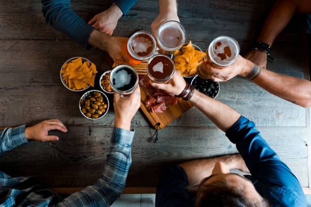 top view of friends sitting over beer at the table in pub - rustic beer brewery indoors imagens e fotografias de stock