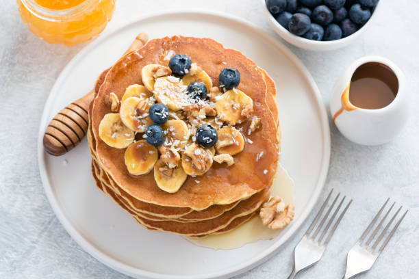 istock Pancakes with blueberries, banana, walnuts and honey on white plate 955998588